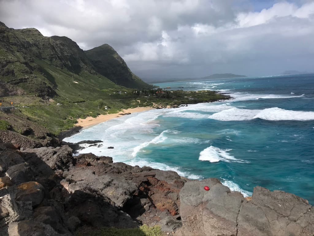 A winding stretch of rocky coastline beneath green mountains on Oahu